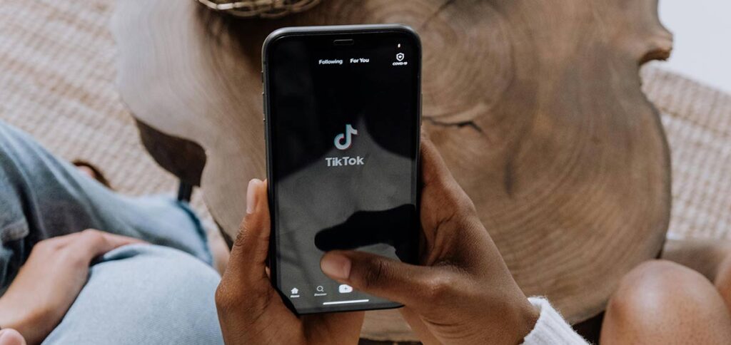 Person holding a smartphone showing opening screen of TikTok app